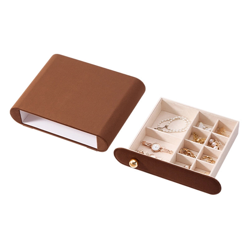 A brown velvet jewelry drawer organizer shown open with pearl bracelets and a watch on a white background.