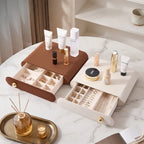 Brown and white leather jewelry drawers on a marble vanity table, styled with high-end luxury cosmetics.