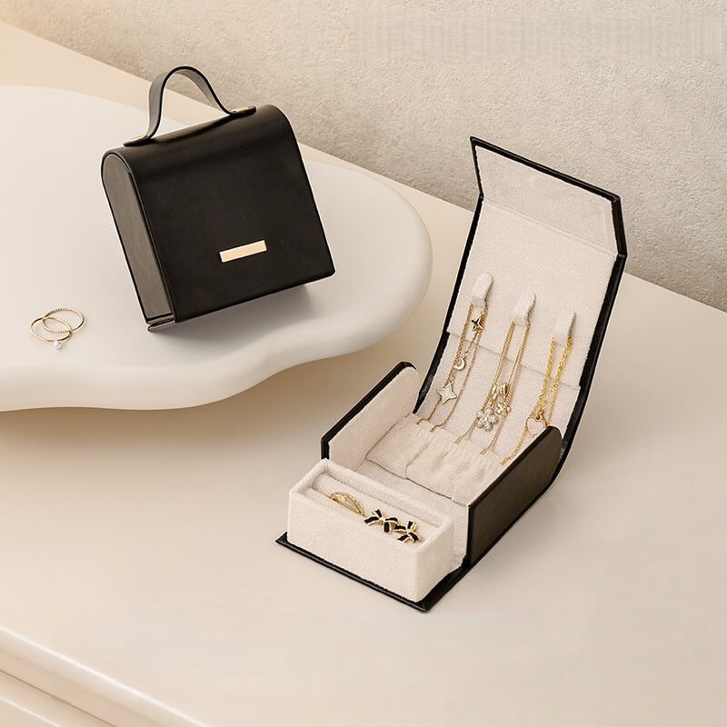 Black handbag jewelry box open showing necklace slots and ring compartment