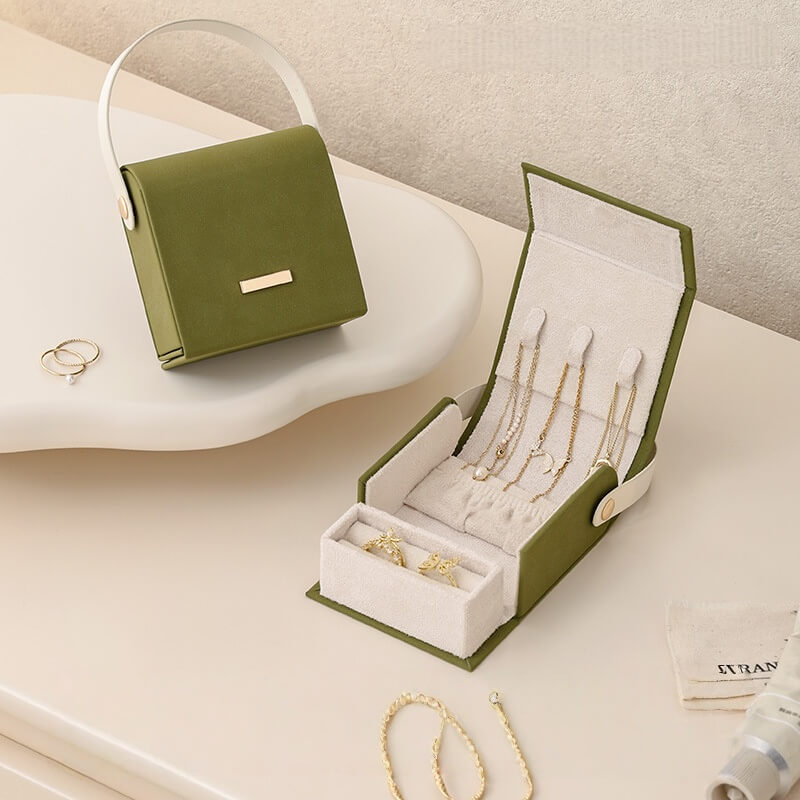 Green handbag jewelry box open showing necklace slots and ring compartment