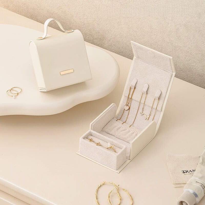 White handbag jewelry box open showing necklace slots and ring compartment