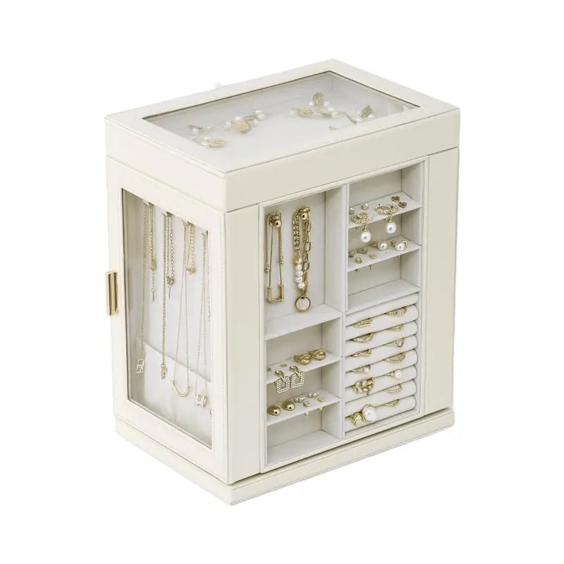 A cream-white leather jewelry organizer case on a pure white background, showcasing individual compartments for bracelets, stud earrings, ring rolls, and a side glass door with hanging necklaces.