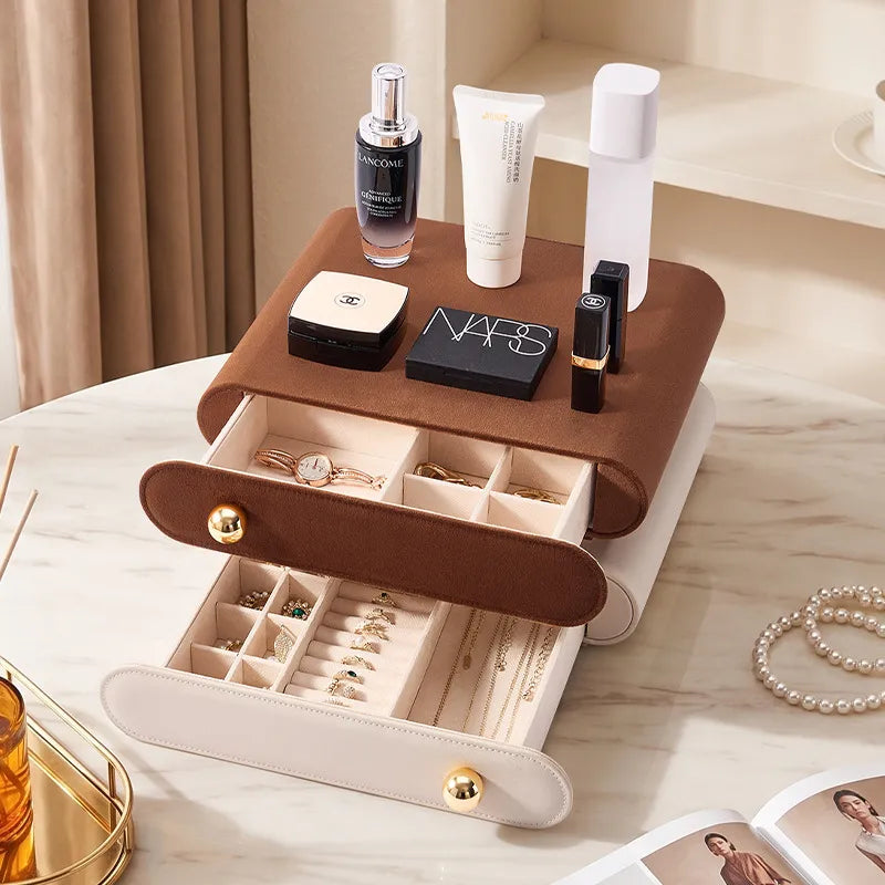Brown and cream white leather jewelry drawers displayed on a marble vanity table, styled with high-end luxury cosmetics, perfume, and a pearl necklace.