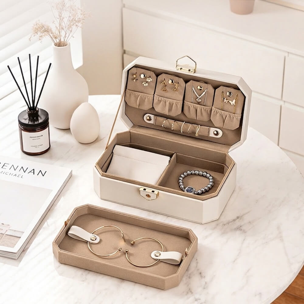 White octagon jewelry box open with removable tray placed in front on marble table, lifestyle scene