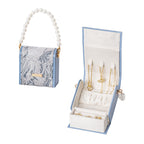3D embroidered jacquard fabric and leather jewelry box with pearl handle, flat lay view