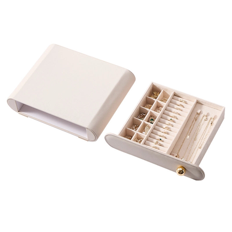 A cream white leather jewelry case with an open drawer filled with organized rings and gold necklaces.