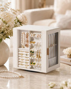 Elegant white leather rotating jewelry box styled on a marble vanity next to a flower vase and pearl necklace.